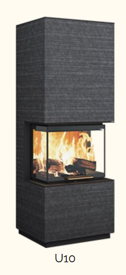 Dreiseitig verglaster Kaminofen (U-Verglasung: Front + beide Seiten), würfelförmige Haube und Sockel. Dunkelgraue, horizontal strukturierte Steinverkleidung, klarer, geradliniger Korpus. Flammenspiel deutlich sichtbar. Freigestellt auf hellem Hintergrund.